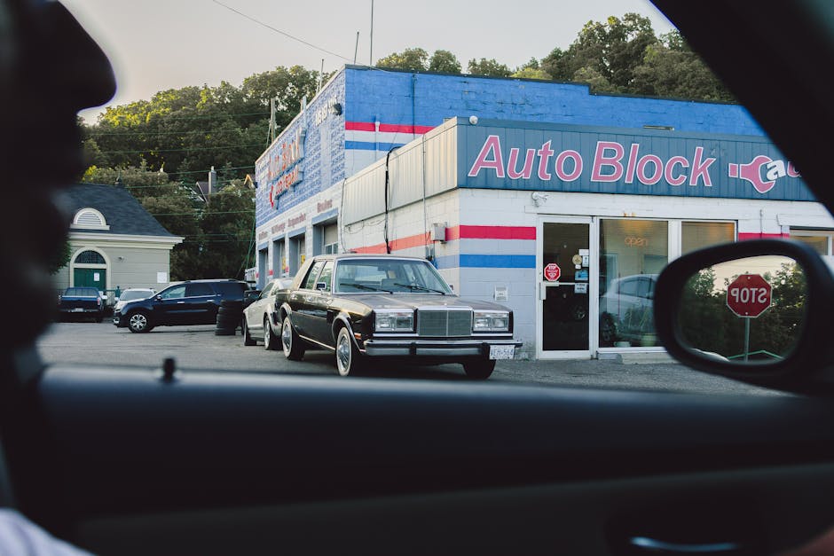 View of an auto repair shop exterior with a classic car in the parking lot.